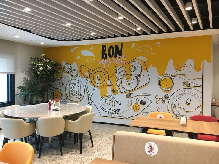 Restaurant wall painting in Newtown Rajarhat with yellow bon appetit mural artwork inside a modern dining space